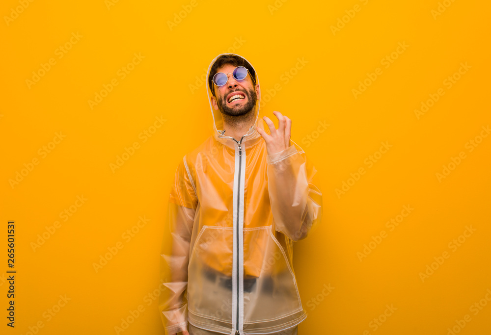 Young man wearing a rain coat very scared and afraid Young man wearing a rain coat very scared and afraid