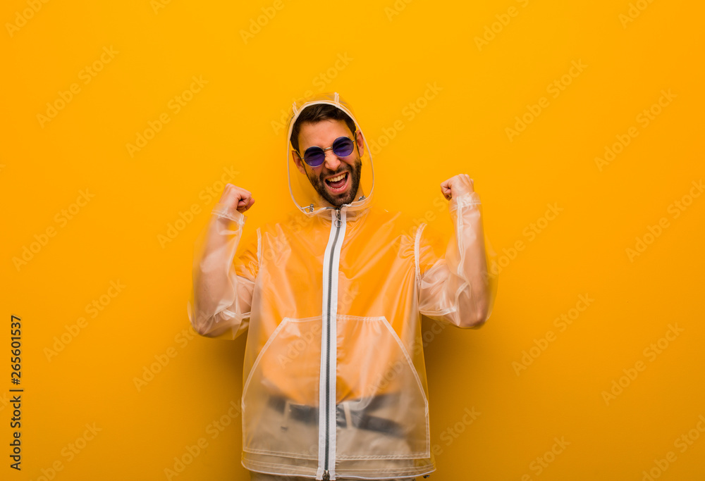 Young man wearing a rain coat surprised and shocked Young man wearing a rain coat surprised and shocked