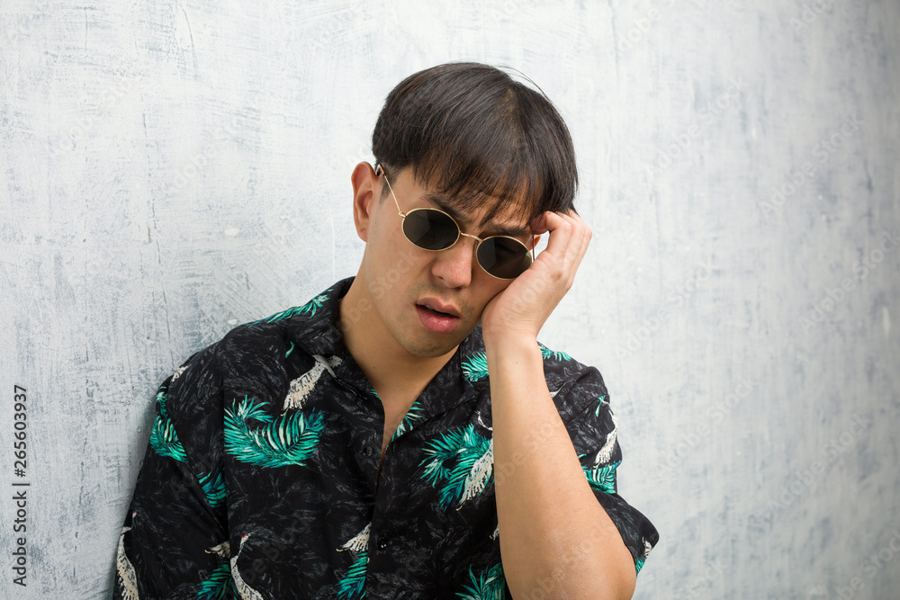 Young chinese man wearing summer outfit tired and very sleepy Young chinese man wearing summer outfit tired and very sleepy