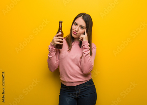 Young cute woman holding a beer thinking about an idea