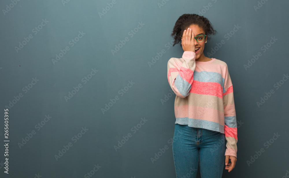 Young african american girl with blue eyes shouting happy and covering face with hand Young african american girl with blue eyes shouting happy and covering face with hand