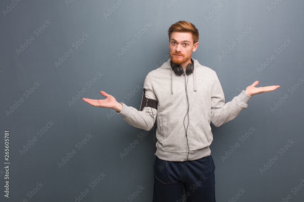 Young fitness redhead man doubting and shrugging shoulders Young fitness redhead man doubting and shrugging shoulders