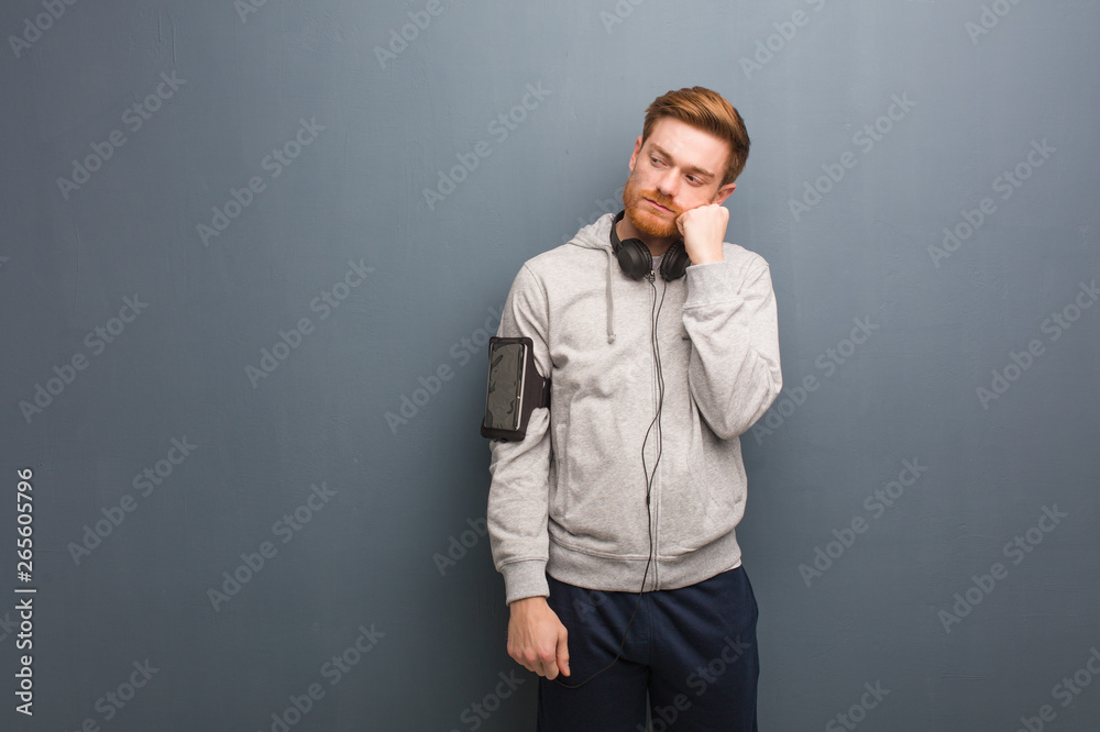 Young fitness redhead man thinking of something, looking to the side Young fitness redhead man thinking of something, looking to the side