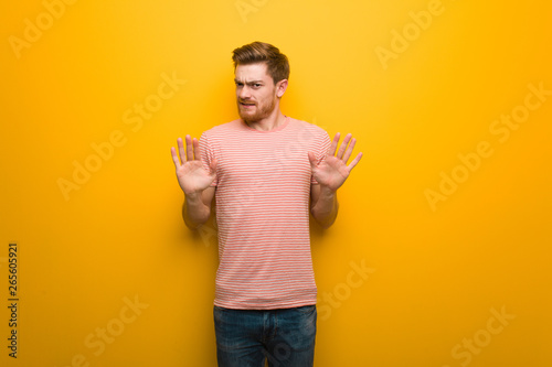 Young redhead man rejecting something doing a gesture of disgust