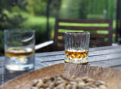 Canvas Print glasses of whiskey and dried fruit plate on table at garden