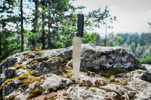hunting knife stuck in the rock in the forest