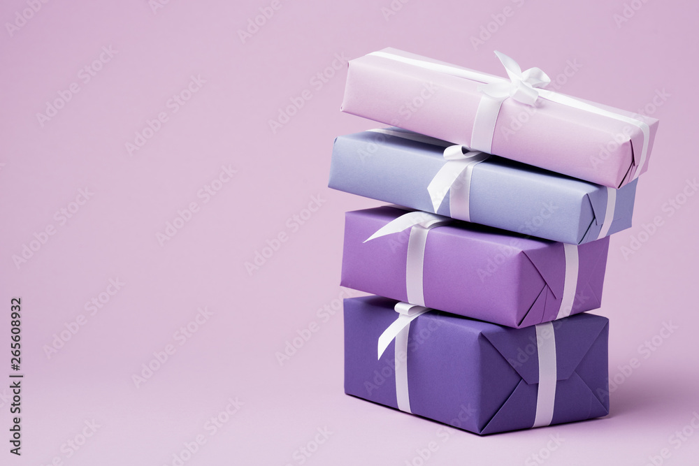 colorful gift boxes with white ribbons on purple surface colorful gift boxes with white ribbons on purple surface