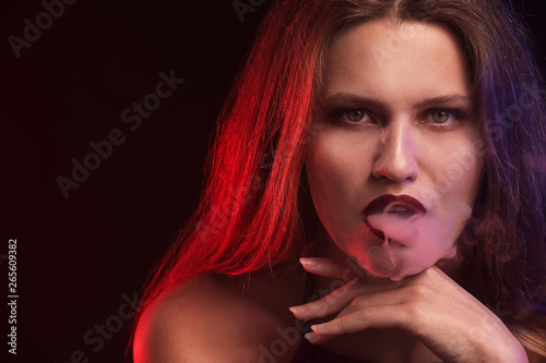 Young woman smoking on dark background © Pixel-Shot