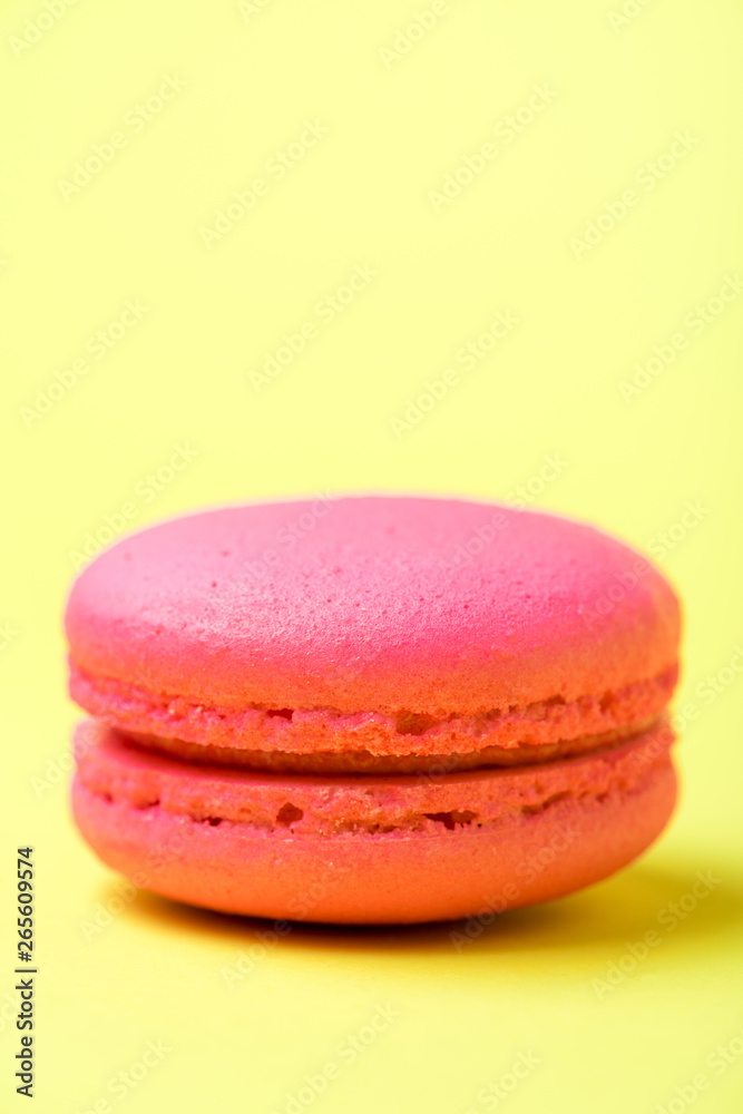 pink macaron cookie with filling on yellow surface pink macaron cookie with filling on yellow surface