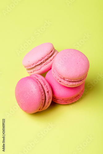 tasty pink macarons with filling on yellow surface
