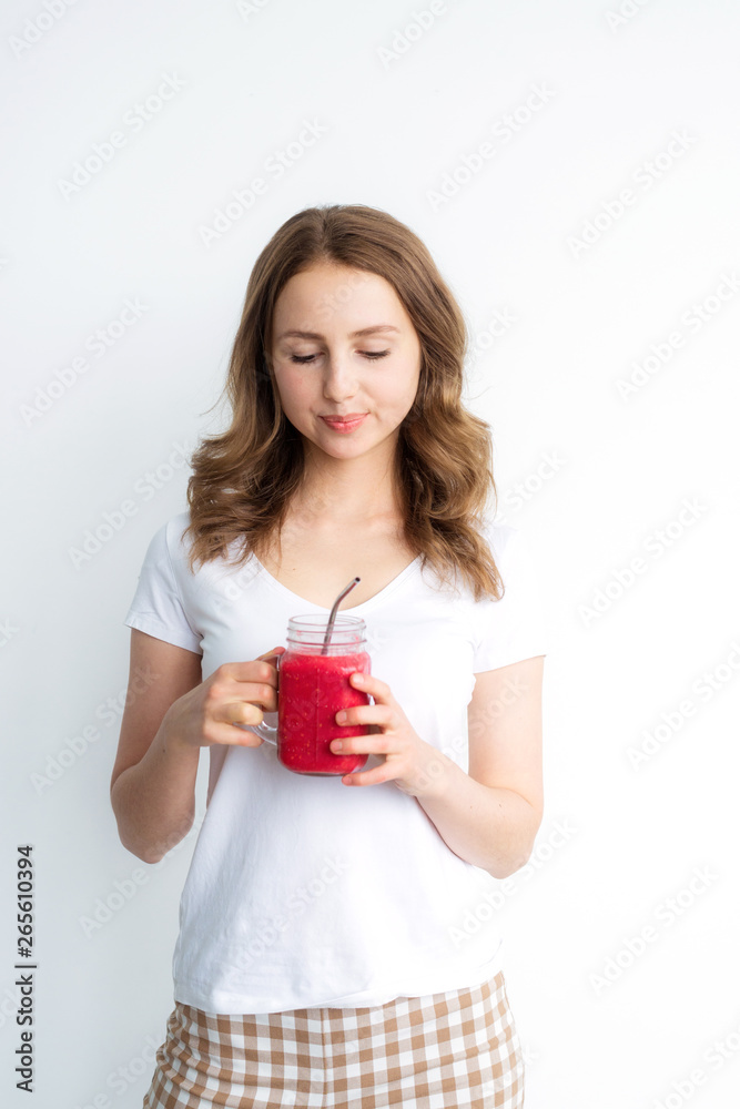 Berry fruit red smoothie in the hands of a young attractive girl on a white background. Berry fruit red smoothie in the hands of a young attractive girl on a white background.