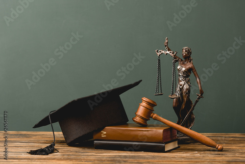 Фотография books, themis statuette, academic cap and gavel on wooden surface isolated on gr