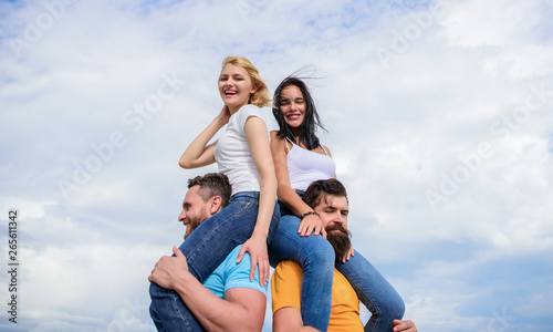 Men carry girlfriends on shoulders. Summer vacation and fun. Couples on double date. Inviting another couple to join. Twice fun on double date. Friendship of families. Couples in love having fun