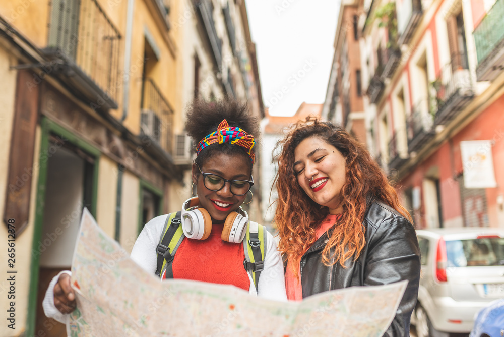 Two Latin Teenage Girls Using a Map and Traveling Together.