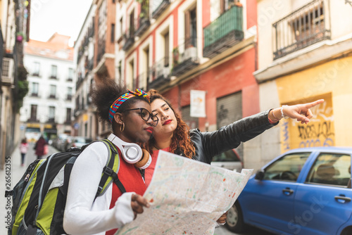 Two Latin Teenage Girls Using a Map and Traveling Together.