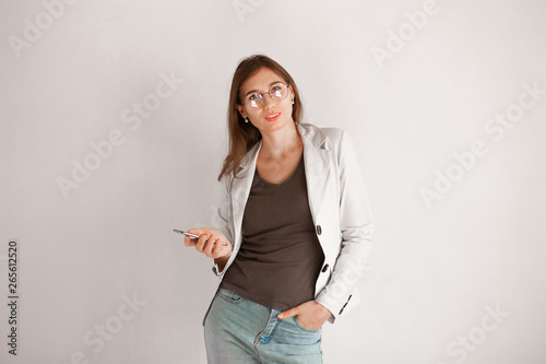 Happy confident young business woman in glasses using smartphone over white background