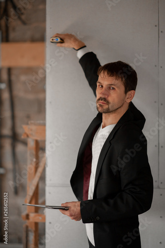 Male realtor measuring room with laser rangefinder