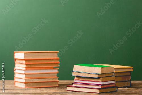 Stacks of colorful books on wooden surface on green