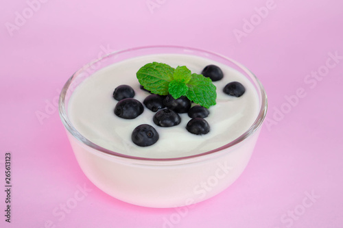 Close up yogurt with fresh blueberries fruit in glass bowl on pink background