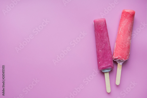 Bright fruit ice cream on a stick on a pink background. Frozen fruit ice. Summer mood. Cooling dessert in hot weather. Favorite delicacy for children. Homemade raspberry, strawberry, watermelon ice