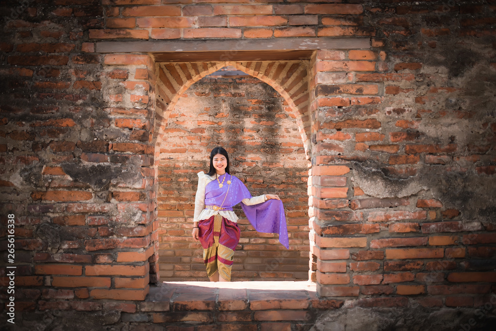 Beautiful Asian women, Thai people wearing Thai clothes, standing on the old wall in the daytime.