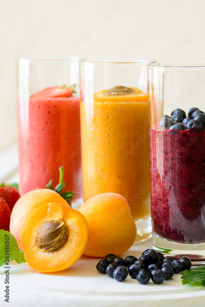 Strawberry, blueberry and apricot smoothies on white wooden background. Detox and healthy eating concept Strawberry, blueberry and apricot smoothies on white wooden background. Detox and healthy eating concept
