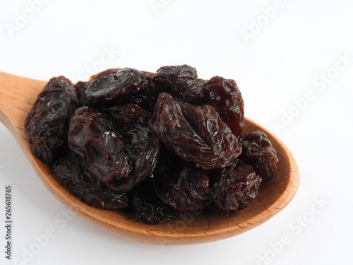 High angle view of raisins on wooden spoon isolated on white background. A raisin is a dried grape Dry food. It tastes sweet and delicious. Texture detail of raisin surface. Food concept.