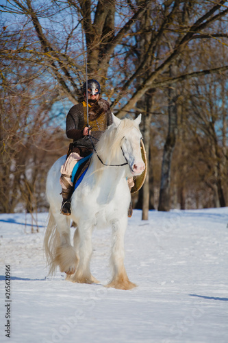 Man in suit of ancient warrior riding big white horse