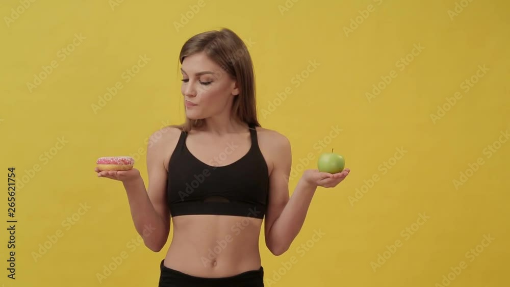 Sporty girl on a diet chooses between a donut and an Apple. Healthy lifestyle Sporty girl on a diet chooses between a donut and an Apple. Healthy lifestyle