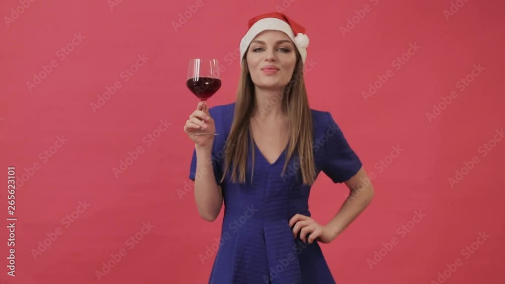 Beautiful girl in Christmas clothes dancing with a glass of wine in her hand. Studio, pink background. Beautiful girl in Christmas clothes dancing with a glass of wine in her hand. Studio, pink background.