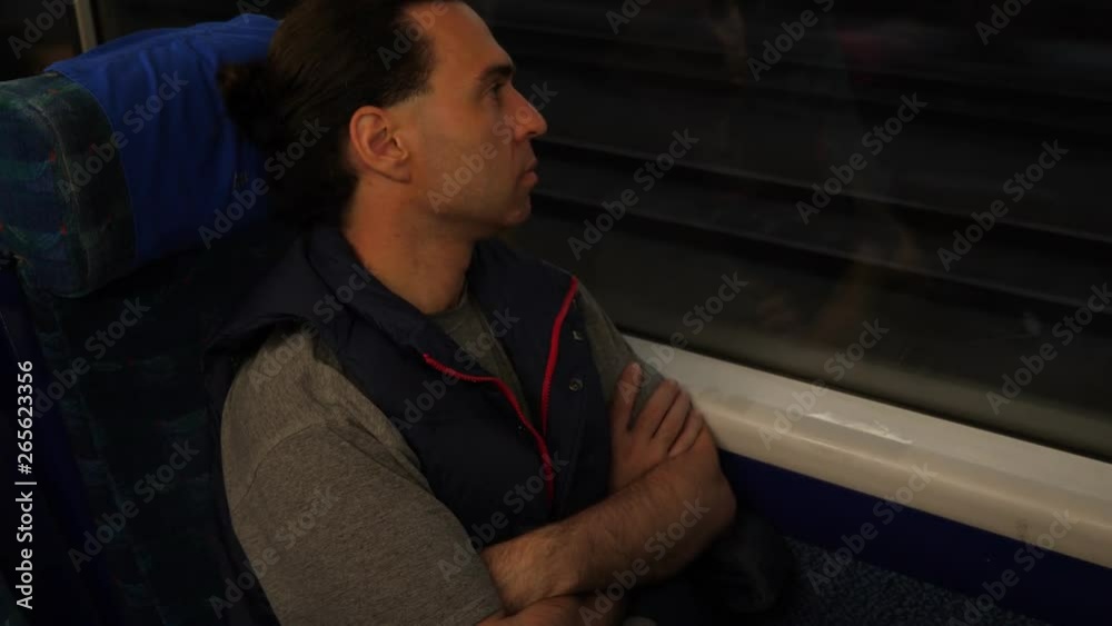 Relaxed passenger sit and lean to train window, look to dark outdoors, other carriage rush towards. Man travel in modern car, perform international route Relaxed passenger sit and lean to train window, look to dark outdoors, other carriage rush towards. Man travel in modern car, perform international route