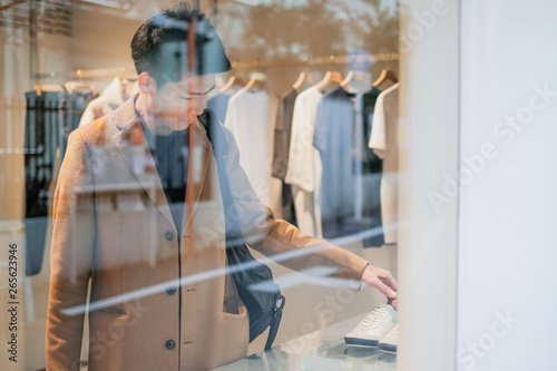 Young man shopping in the clothes shop. Looking through the window