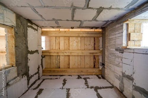 Close-up detail of house room interior under construction and renovation. Energy saving walls of hollow foam insulation blocks, wooden ceiling beams for roof frame. © bilanol