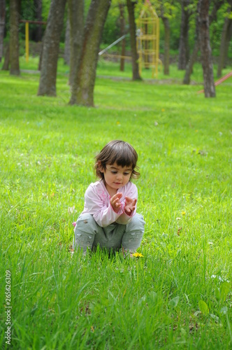 A little girl is playing in the grass in the park