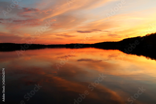 Calm lake water with bright orange sunset casting reflection.