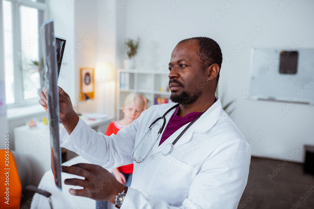 Fototapeta premium Dark-eyed doctor feeling concerned while checking x-ray of girl