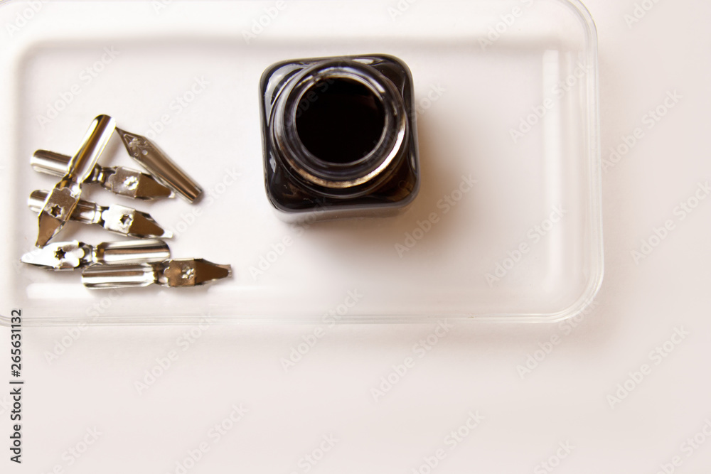 ink bottle with metal tips for ink pen on a white background. stationery on white desk close up top view. spelling lessons and caligraphy exercises. Template, layout, background ink bottle with metal tips for ink pen on a white background. stationery on white desk close up top view. spelling lessons and caligraphy exercises. Template, layout, background