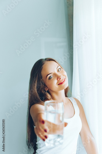 Closeup young woman show glass of water. Portrait of happy smiling female model  holding transparent glass of water.Healthy lifestyle. Beauty  Diet concept