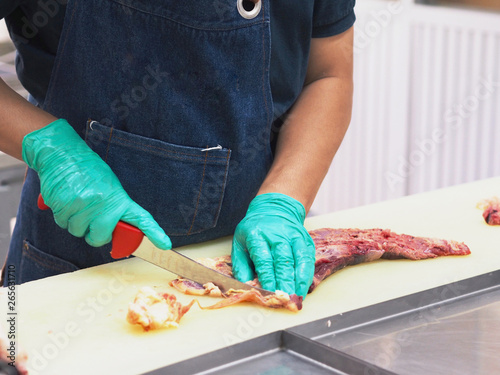 Master chef butcher is dissecting part of meat tenderloin , slicing membrane. photo