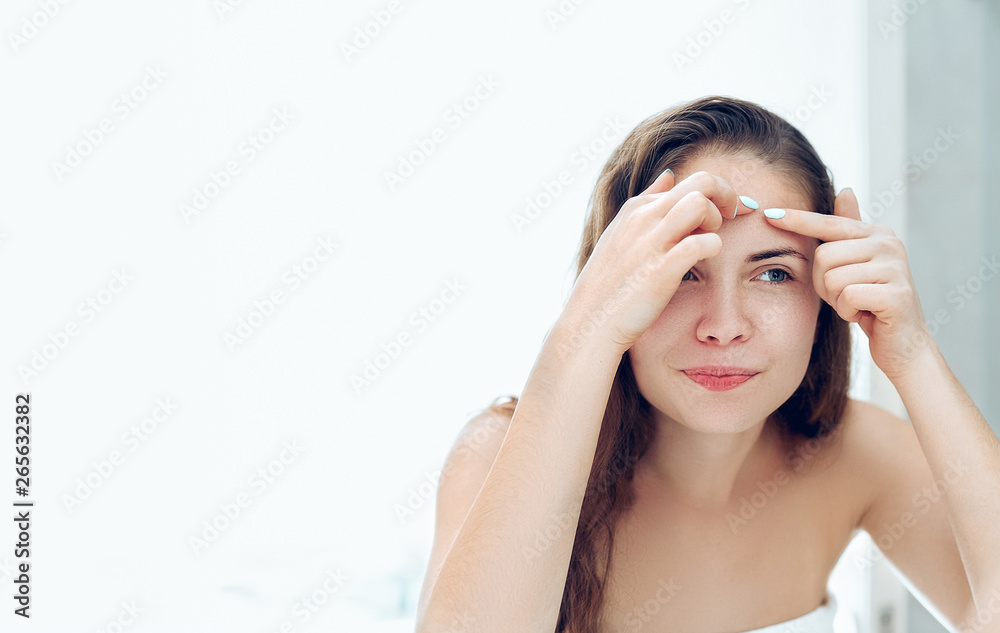 Young woman looking and squeeze acne on a face in front of the mirror. Ugly problem skin girl, teen girl having pimples. Skin care. Beauty Young woman looking and squeeze acne on a face in front of the mirror. Ugly problem skin girl, teen girl having pimples. Skin care. Beauty