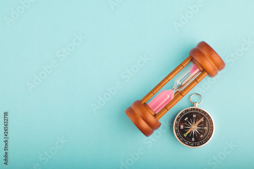 hourglass and compass on blue background for direction or running out of time concept, copy space for text