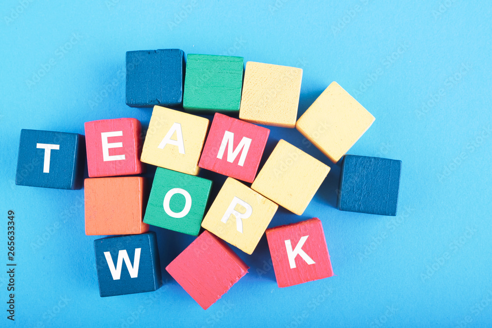 TEAMWORK word on wooden cube over blue background for cooperation, togetherness or partnership concept TEAMWORK word on wooden cube over blue background for cooperation, togetherness or partnership concept