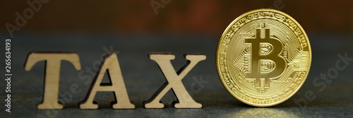 Bitcoin and wooden letters TAX on stone background