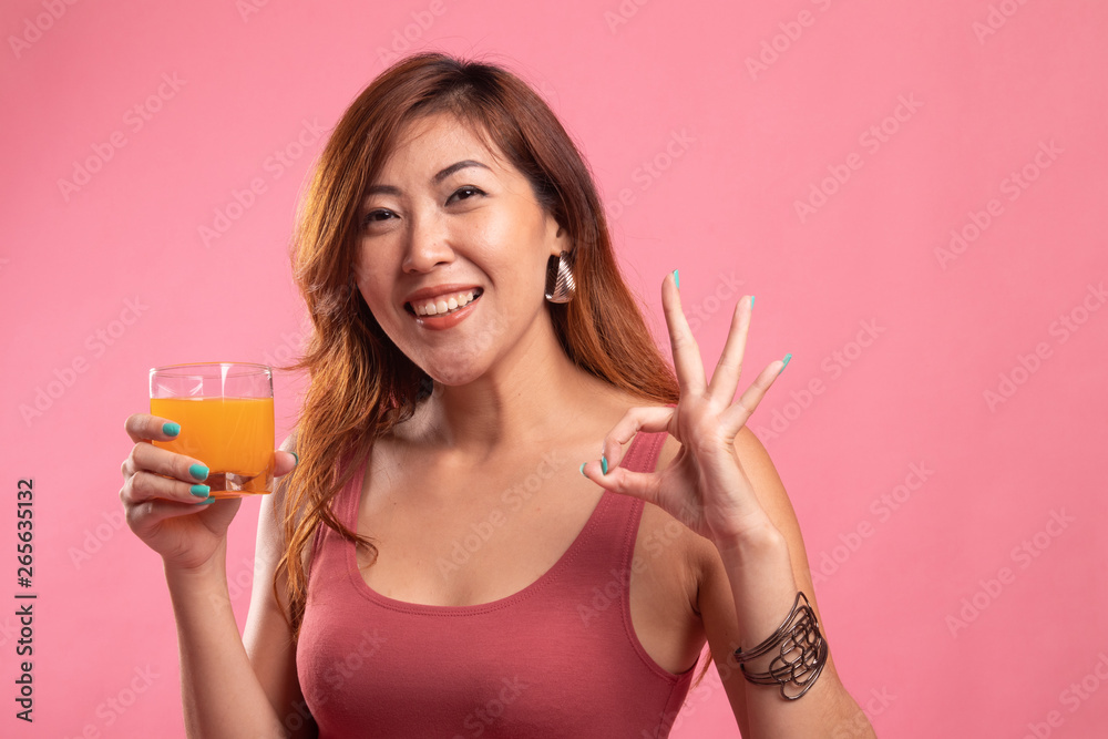 Young Asian woman drink orange juice show OK sign.