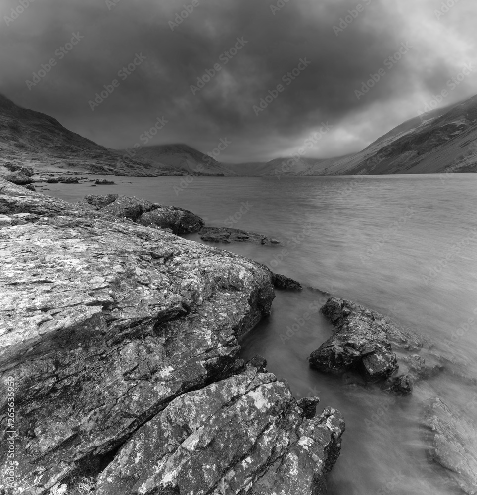 Stunning long exposure landscape image of Wast Water in UK Lake District during moody Spring evening in black and white