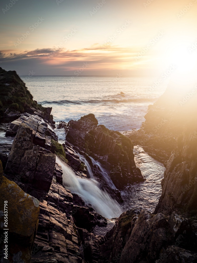 Obraz premium Sunset over a coastal waterfall