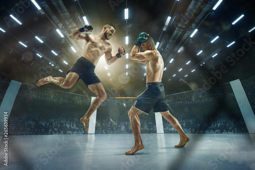 Last moment before winning. Two professional fighters posing on the sport boxing ring. Couple of fit muscular caucasian athletes or boxers fighting. Sport, competition and human emotions concept.