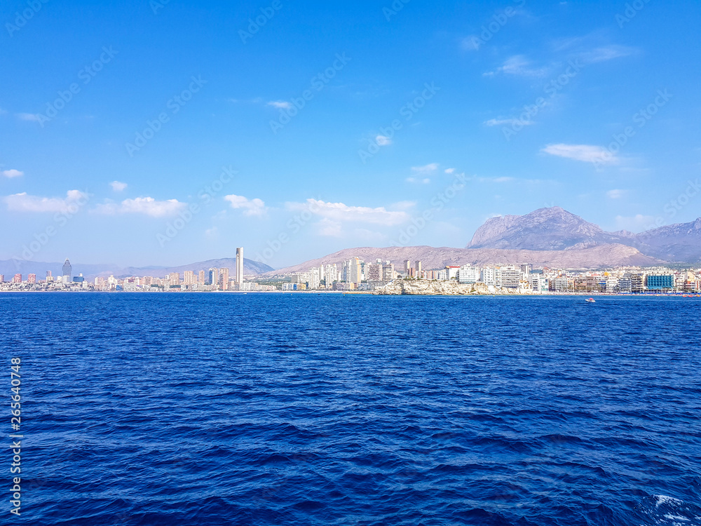Beautiful Levante beach in Benidorm, Spain. Image taken from the sea, with the skyline of skyscrapers and a boat of first motive. Concept of holidays in Benidorm.