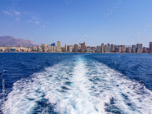 Beautiful Levante beach in Benidorm, Spain. Image taken from the sea, with the skyline of skyscrapers and a boat of first motive. Concept of holidays in Benidorm.