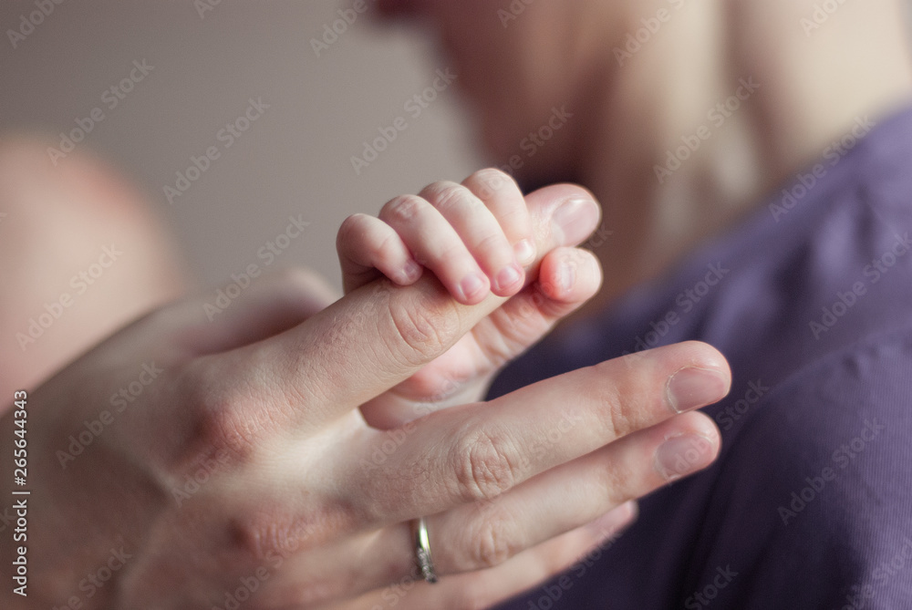 parent and newborn baby hands. Newborn baby holds mother's finger, wedding ring on finger, family